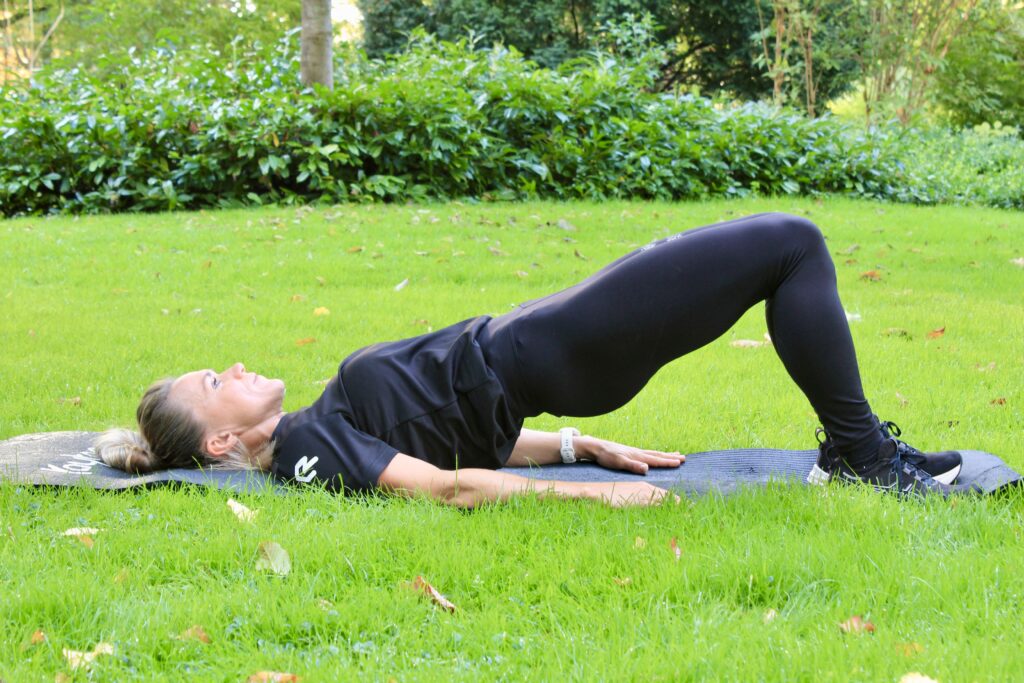 glute bridge door lianne uitgevoerd op een grasveld